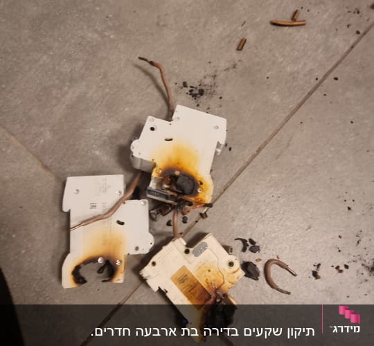 מפסקי חשמל שרופים עם חוטים על רצפה אפורה
